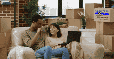 man and woman sitting on couch surrounded by boxes after a long distance move