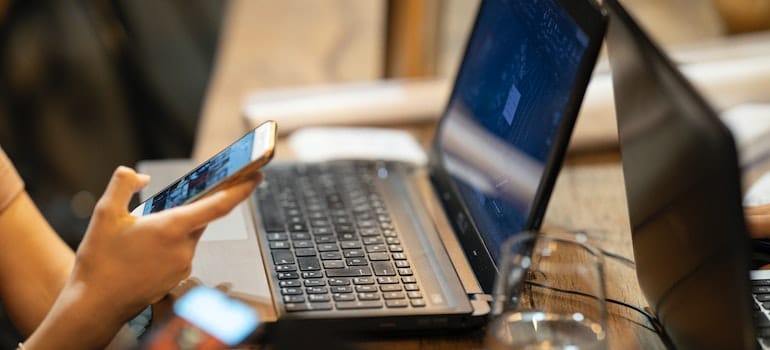 A person using laptop and a phone to research about moving from Connecticut to Pennsylvania