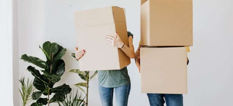 A couple holding boxes while waiting for movers Norwalk CT offers