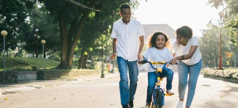 Parents teaching a girl to ride a bike