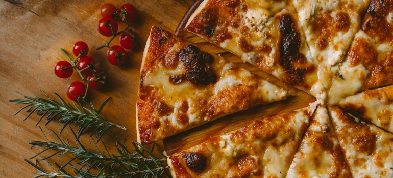 Pizza, tomatoes and rosemary on a wooden surface 