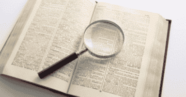 Magnifying glass over dictionary page revealing moving terminology definitions