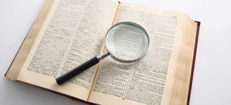 Magnifying glass over dictionary page revealing moving terminology definitions