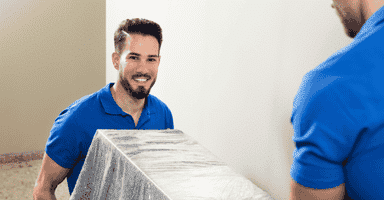 Collegian Movers offers reliable hourly movers near you to handle packing, lifting, and loading with professional care. In this image, two trained movers carry a large box during a residential move, demonstrating teamwork and efficiency for local Connecticut moves.